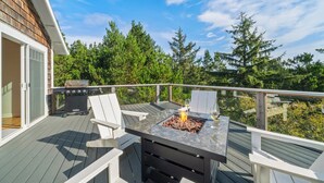 Terraza exterior con una parrilla, dos sillas y una mesa con chimenea.