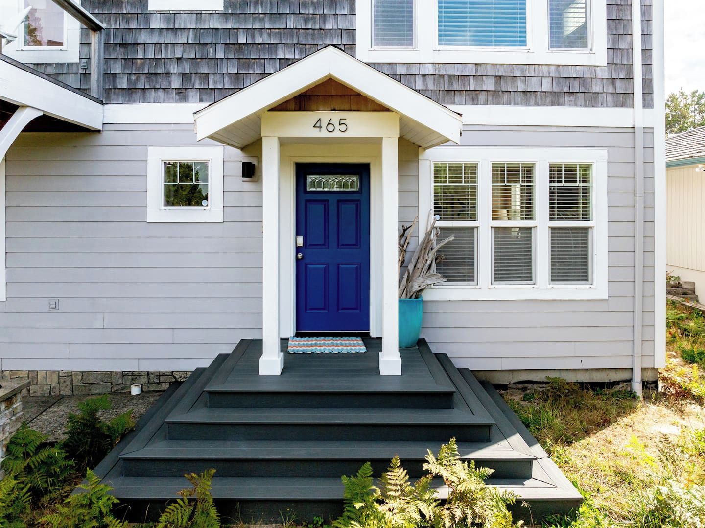 A house with a blue front door, a number '465' above it, and a small porch with steps leading up to the door.