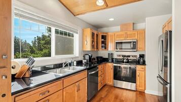 A modern kitchen with wooden cabinets, stainless steel appliances, and a large window.