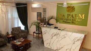 Uma área de recepção com balcão de mármore, ventilador de teto e placa na parede para Da Palm Boutique Resort.