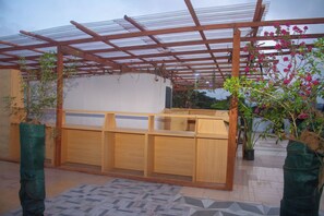 A covered outdoor seating area with wooden benches and a metal roof.