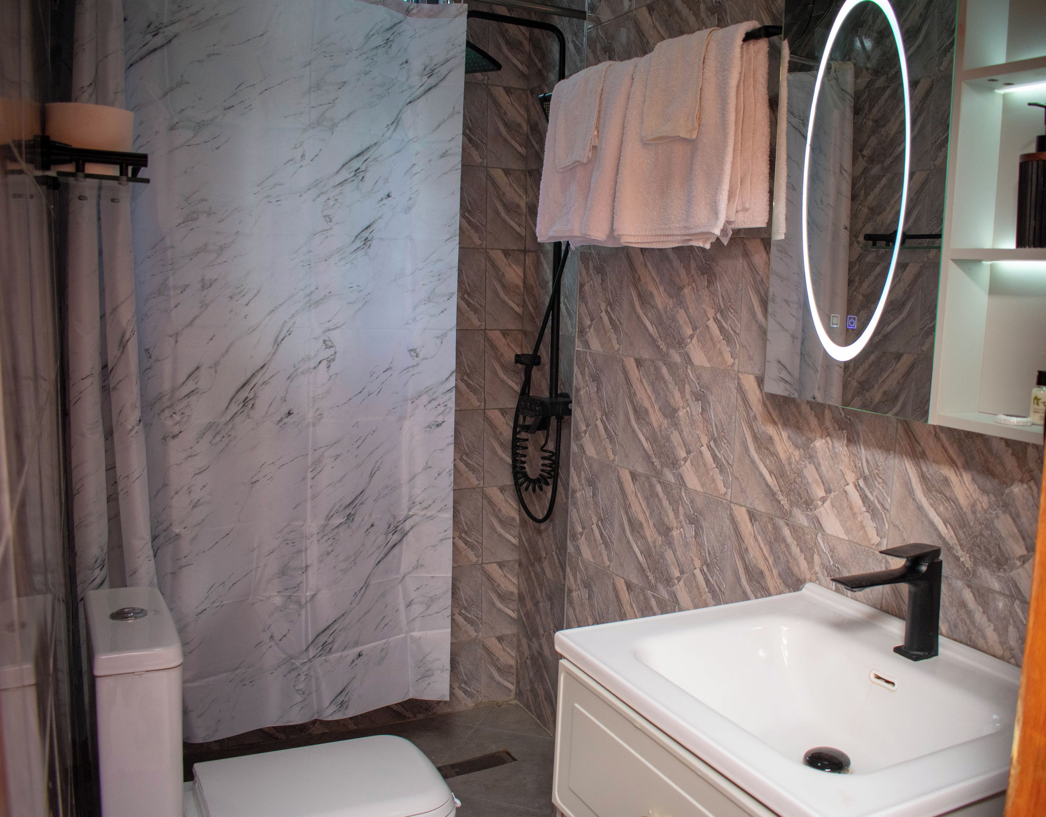 A bathroom with a white sink, a mirror, a shower curtain, and a towel rack.