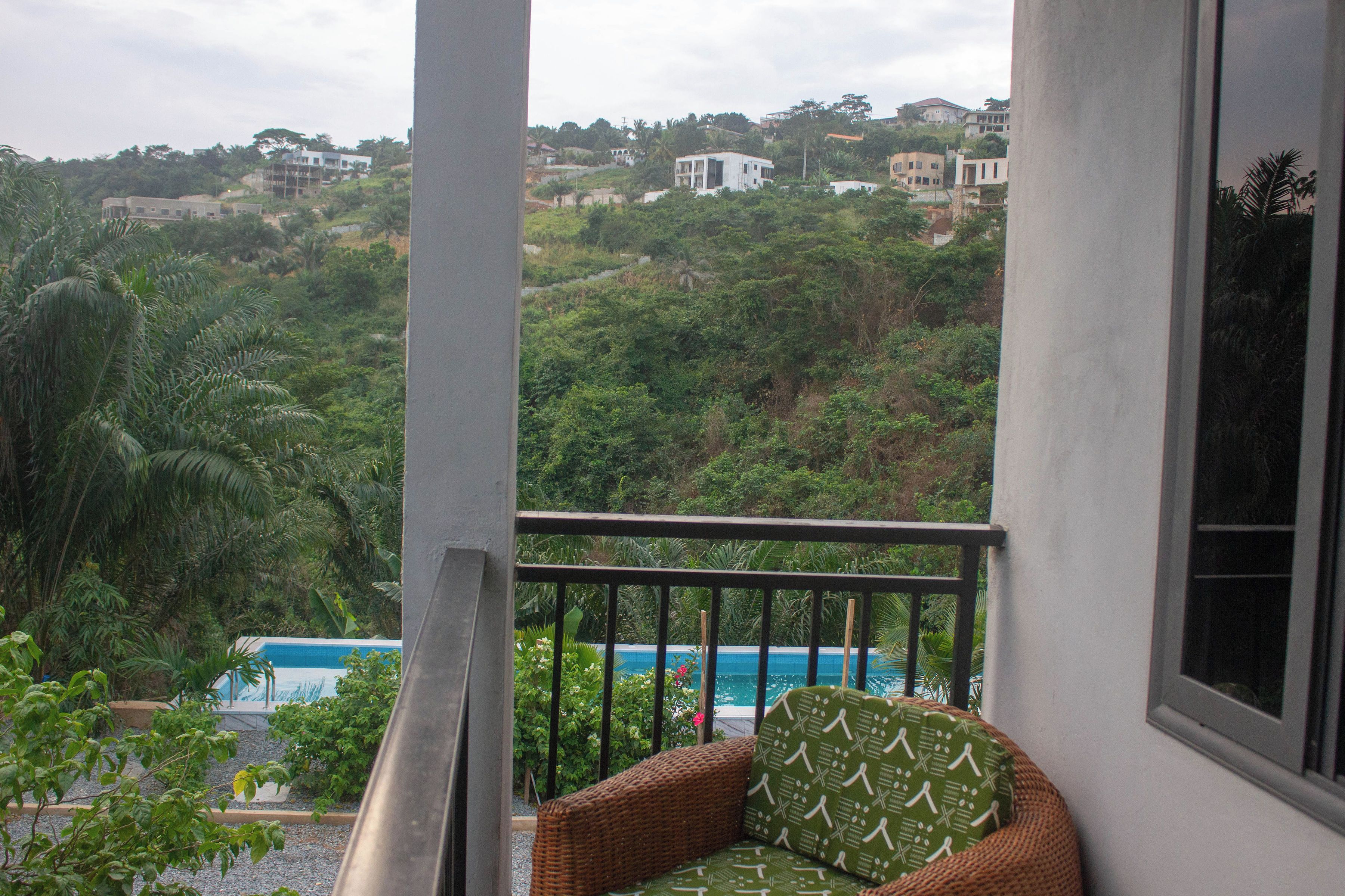 A balcony with a view of a swimming pool and lush greenery.