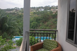 Un balcon avec vue sur une piscine et une végétation luxuriante.