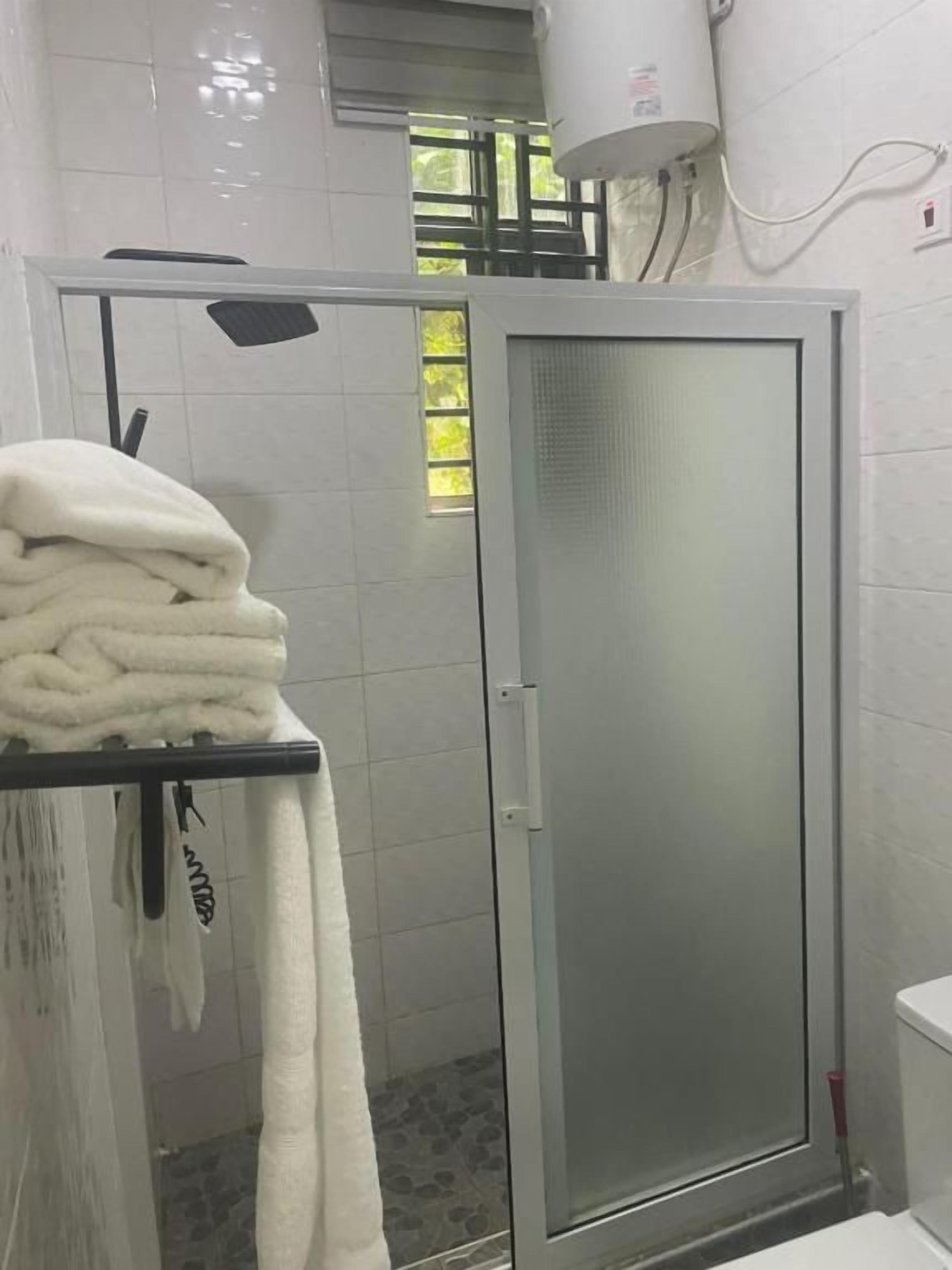 A bathroom with a glass shower door, a towel rack with towels, and a white toilet.