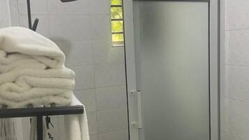 A bathroom with a glass shower door, a towel rack with towels, and a white toilet.