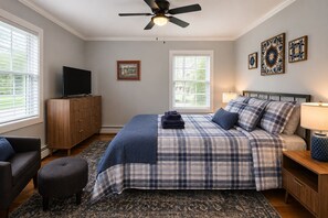 A bedroom with a bed, a television, a ceiling fan, and artwork on the wall. - Fully Renovated 4BR Home, 2 Baths, Deck, Parking (Saratoga Springs)