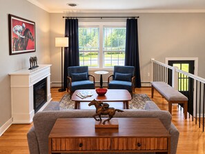 A living room with a fireplace, two blue armchairs, a coffee table, and a sofa. - Fully Renovated 4BR Home, 2 Baths, Deck, Parking (Saratoga Springs)