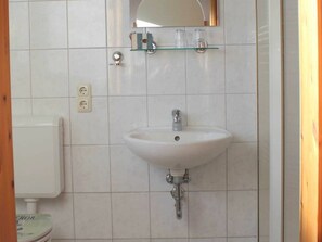 A bathroom with a white sink, a mirror above it, and a toilet to the left. - Holiday Apartment With 1 Bedroom (Hasselberg)