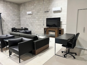A modern living room with a sectional sofa, a flat-screen TV, a fireplace, and a dining area. - Modern industrial guest suite in the heart of downtown Melbourne (Melbourne)