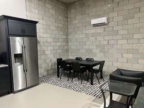A compact kitchen with a stainless steel refrigerator, a dining table with chairs, and a black leather sofa. - Modern industrial guest suite in the heart of downtown Melbourne (Melbourne)