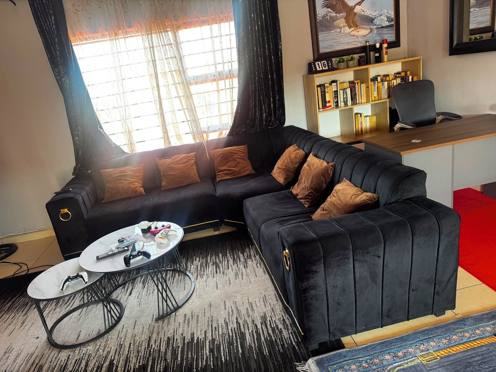 A modern living room with a black sofa, a coffee table, and a bookshelf.