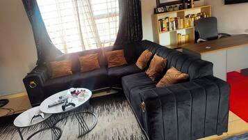 A modern living room with a black sofa, a coffee table, and a bookshelf.