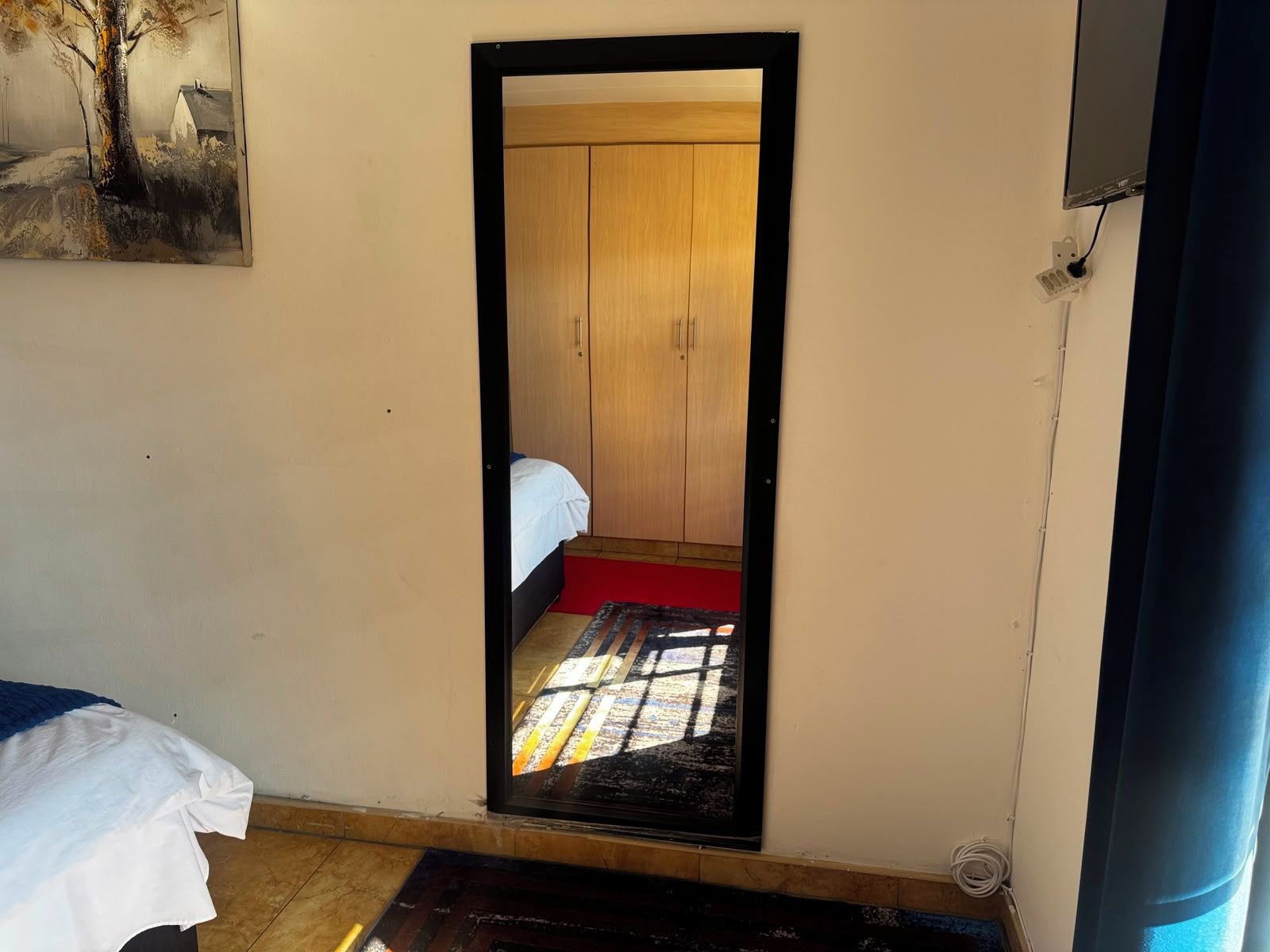 Un estrecho acceso que da a una habitación con una cama y un armario de madera.