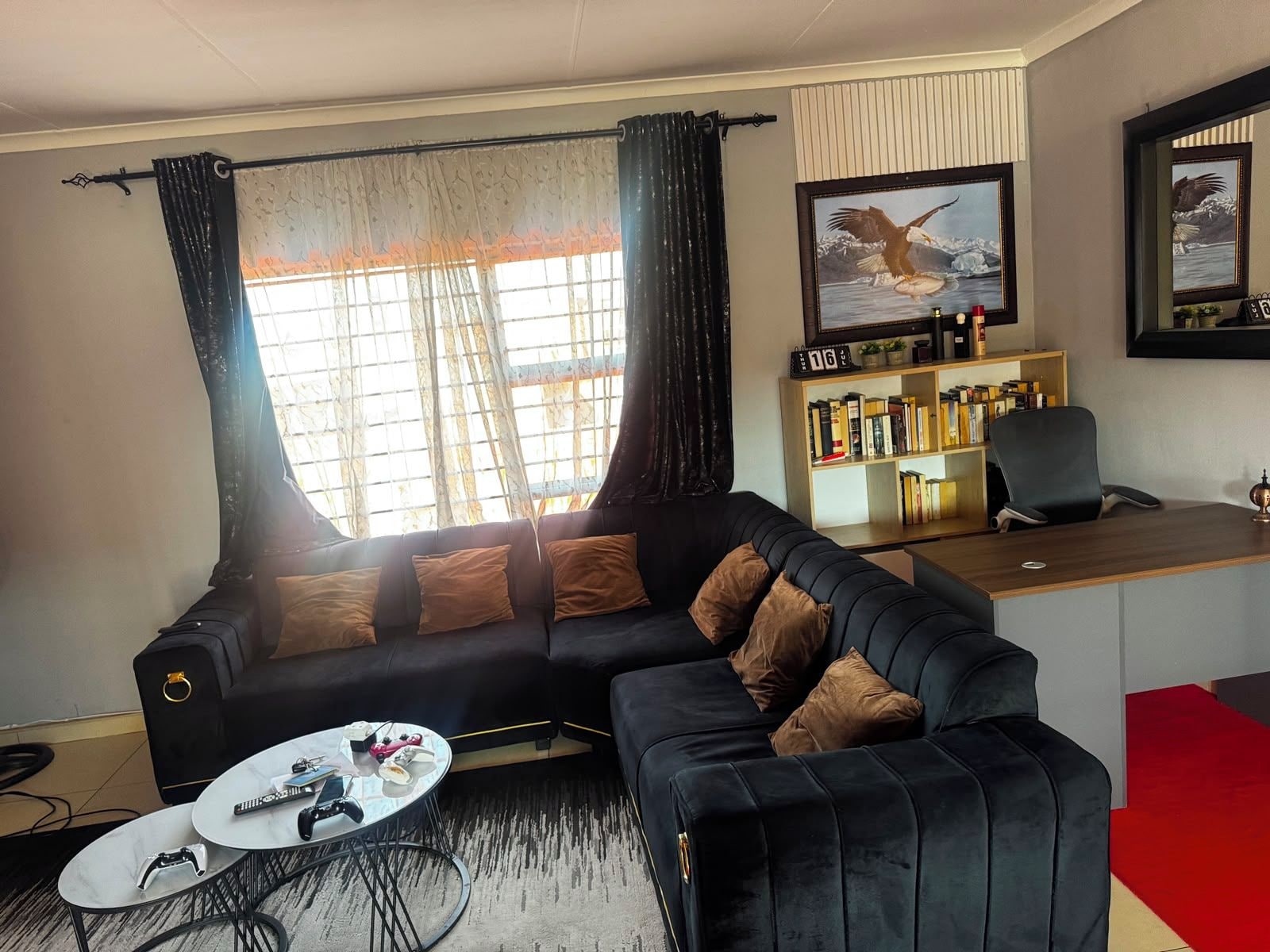 Ein Wohnzimmer mit einer schwarzen Couch, einem Couchtisch und einem Bücherregal.