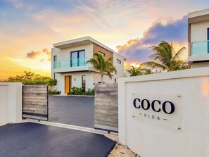 Ein modernes, zweistöckiges Haus mit einem eingannten Eingang und einem Schild mit der Aufschrift 'COCO'.