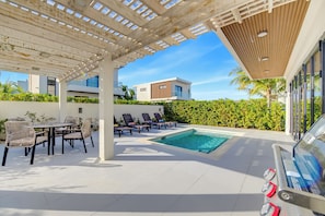 A covered outdoor area with a pool, lounge chairs, and a table with chairs. - 25% Off Oct 7-15, Private Pool, Walk 2 Beach/Shops (Grace Bay)