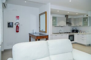 A modern kitchen with white cabinets, a stove, and a microwave.