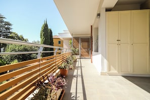 A balcony with a wooden railing, potted plants, and a view of a building in the background. - Modern Design & Panoramic View in Velletri (Velletri)