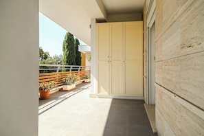 A corridor with a sliding door leading to a balcony with potted plants and a wooden fence.