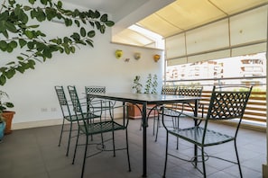 A dining area with a table and chairs, potted plants, and a view of buildings through a window. - Modern Design & Panoramic View in Velletri (Velletri)