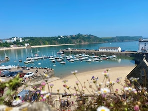 A coastal marina with boats, a sandy beach, and a stone wall.