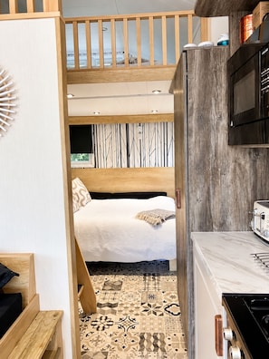 A compact kitchen with a microwave, stove, and wooden counter.