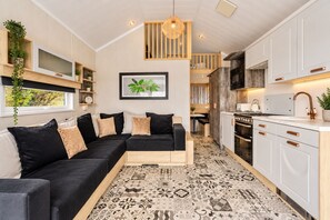 Une cuisine moderne avec des meubles blancs, un plan de travail noir et un luminaire suspendu.