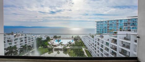 A high-rise hotel with a view of the sea and a pool area.