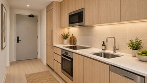 Eine moderne Küche mit Holzschränken, einer eingebauten Mikrowelle, einer Spüle und einem Geschirrspüler.