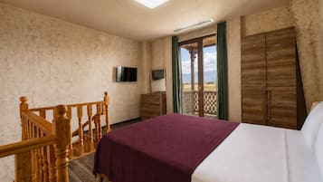 A bedroom with a bed, wooden furniture, a television, and a view of the outdoors.