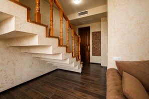 A staircase with wooden balusters leading to a landing, a patterned wall, and a brown leather sofa.
