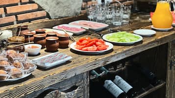 A bar area with a variety of food items, including sliced tomatoes, a plate of sliced cucumbers, and several small bowls of condiments.