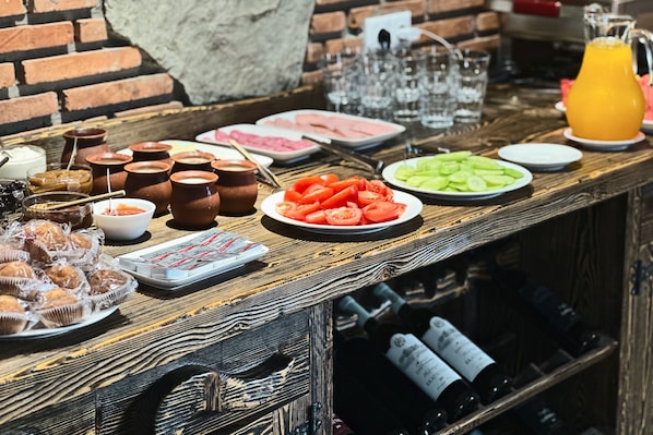 A bar area with a variety of food items, including sliced tomatoes, a plate of sliced cucumbers, and several small bowls of condiments.