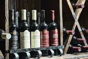 A rack of wine bottles with labels, some with corks, in a wooden setting.