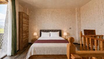 Habitación de hotel con cama, dos lámparas de noche, cabecera de madera, vista al exterior y una escalera de madera.