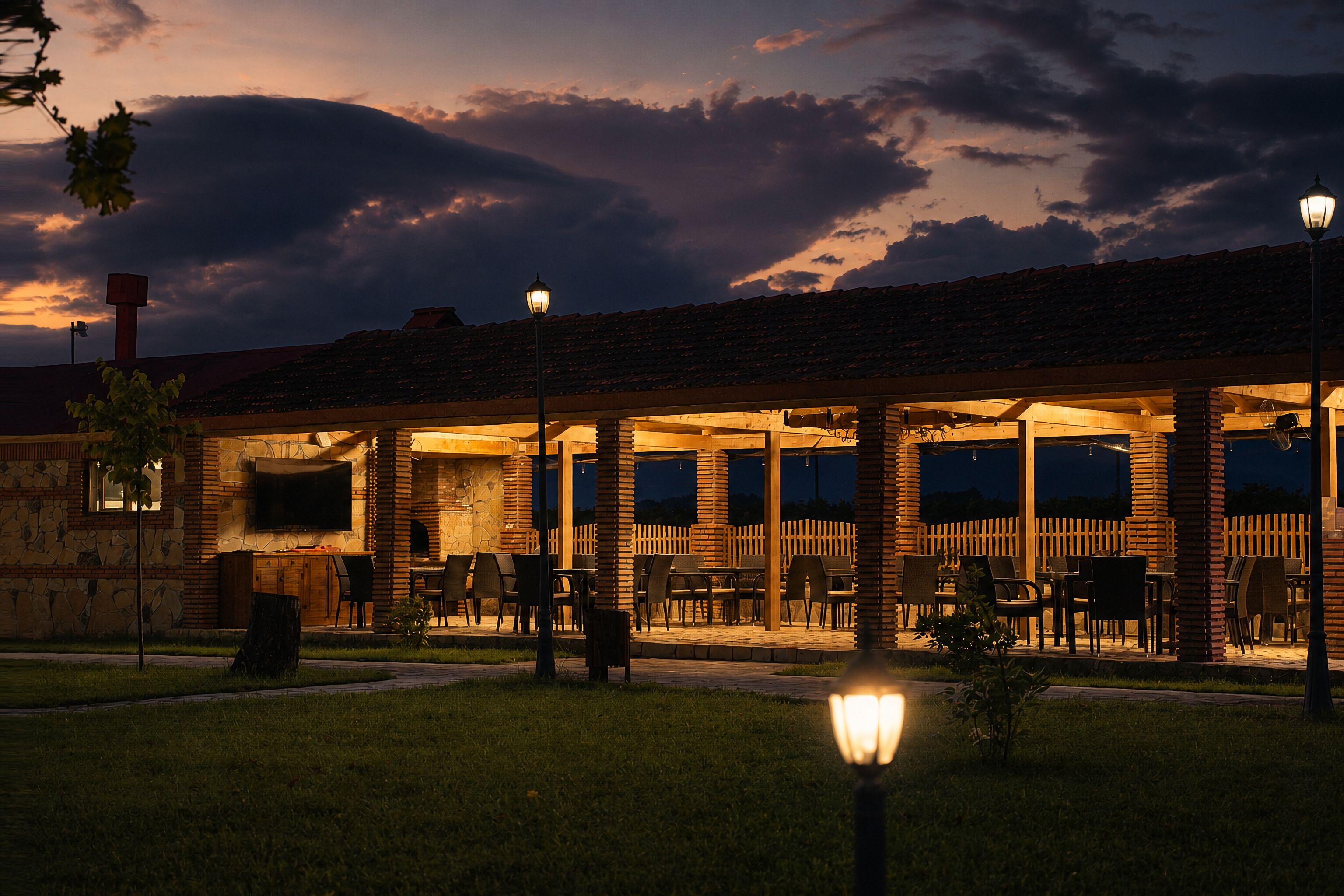 An outdoor patio area with tables and chairs, a stone wall, and a wooden fence.