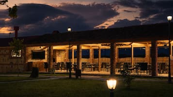 Un área de patio al aire libre con mesas y sillas, un muro de piedra y una valla de madera.