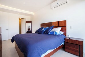 Ein modernes Schlafzimmer mit einem großen Bett, einem Holzkopfteil und einem Nachttisch mit Schublade.