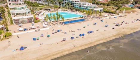 A resort with a large pool, beach, and multiple buildings.