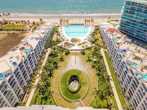 Un resort con piscina central, una fuente acuática circular y una zona de playa.