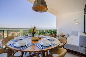 Un comedor con una mesa redonda dispuesta para cuatro personas, rodeada de sillas de mimbre, una lámpara colgante de mimbre y vistas al paisaje.