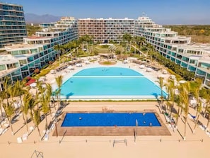 A hotel with a large central pool, multiple balconies, and a beach area. - 2 Bedroom with Gorgeous Pool and views at Aria (Nuevo Vallarta)