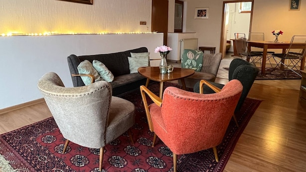 Un salon comprenant un canapé, deux fauteuils, une table basse et un coin repas avec une table et des chaises.