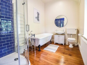 A bathroom with a glass shower enclosure, a white bathtub, a white toilet, and a sink with a mirror above it. - Dolhiryd (Llangollen)