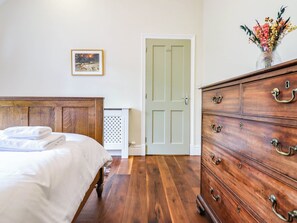 A bedroom with a wooden bed, a dresser, a door, and a framed picture on the wall. - Dolhiryd (Llangollen)