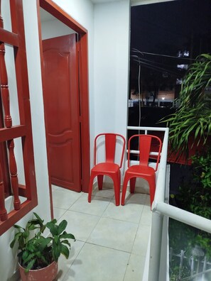 A balcony with two red plastic chairs, a potted plant, and a red door. - Just two blocks from San Felipe Castle! A cozy and warm apartment (Cartagena de Indias)