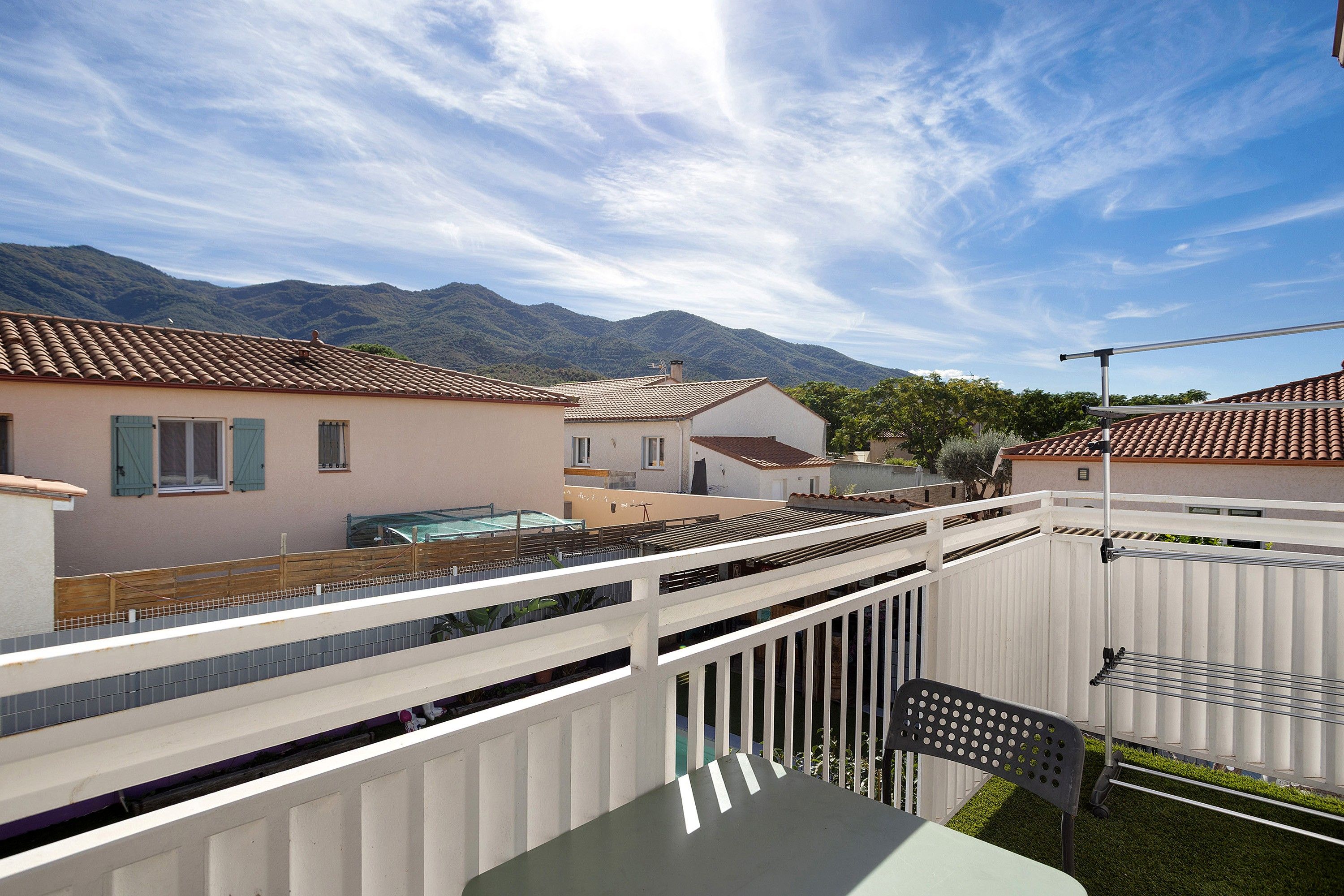A residential area with houses, a white fence, and a table with a chair.