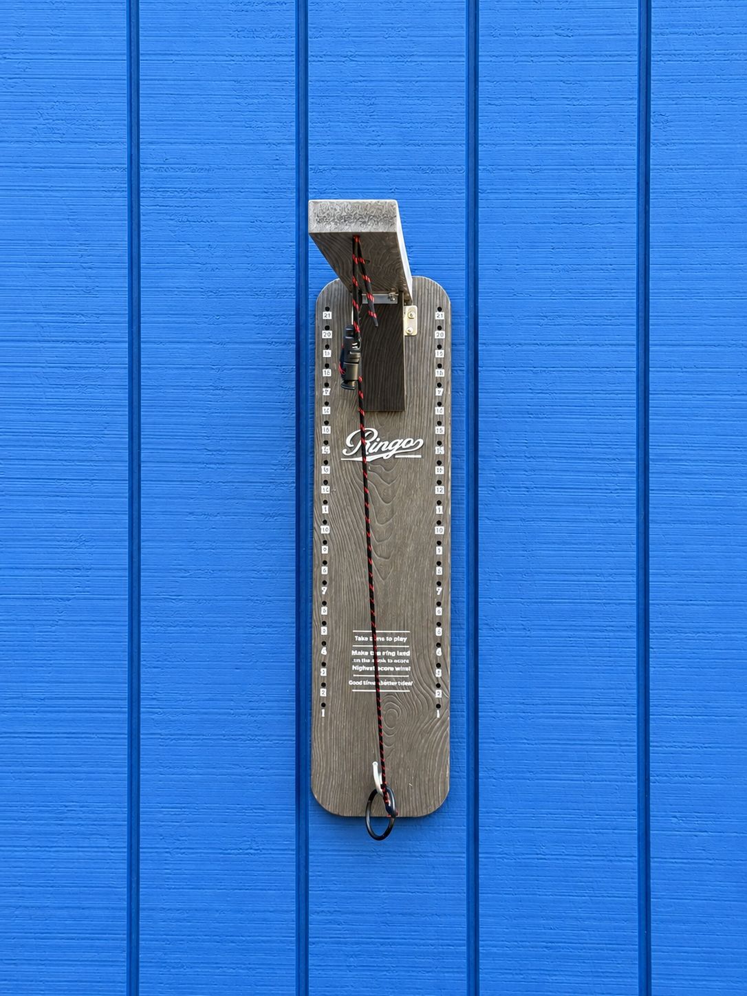 Ein Skateboard mit dem Schriftzug 'Ringo', angebracht an einer blauen Wand.