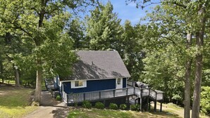 Een huis met een terras en een overdekte veranda, omgeven door bomen.
